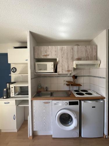 a kitchen with a washing machine and a microwave at Charmant appartement avec vue montagne in Luz-Saint-Sauveur