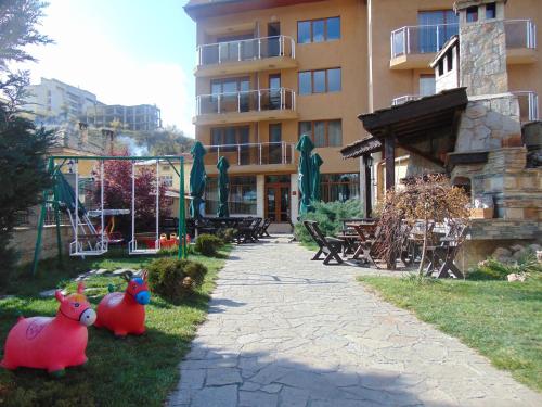 two pink plastic pigs sitting in the grass in front of a building at Meteor Family Hotel in Chepelare
