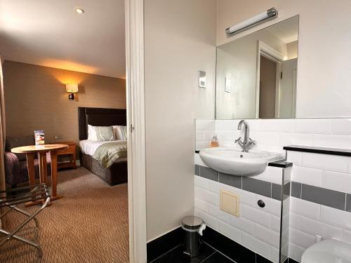 a bathroom with a sink and a bedroom with a bed at Goswell House Hotel central Windsor in Windsor