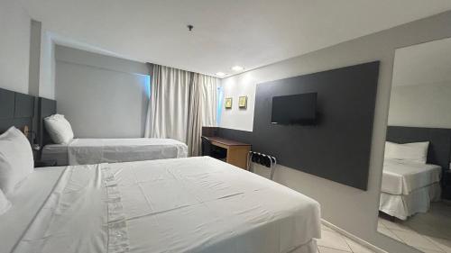 a hotel room with two beds and a flat screen tv at Natal Plaza Hotel in Natal