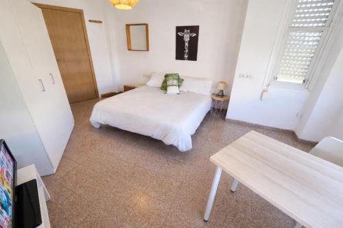 a bedroom with a white bed and a table at eXperience Rooms Valencia in Valencia