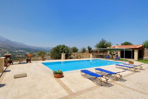 a swimming pool with two blue lounge chairs next to it at Villa Georgia in Fílippos