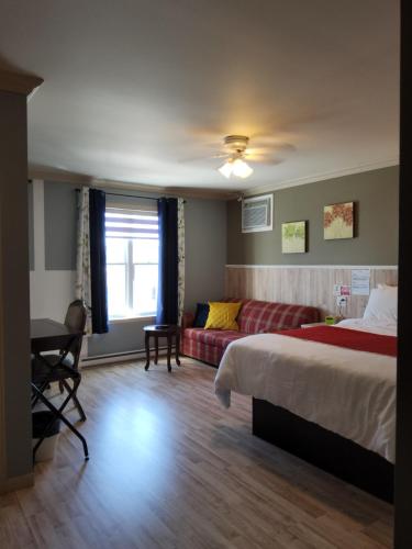 a hotel room with a bed and a couch at Petit Hôtel Amara in La Malbaie