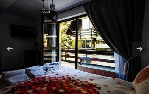 a bedroom with a bed and a large window at Apartament Kalinderu K2 Busteni in Buşteni