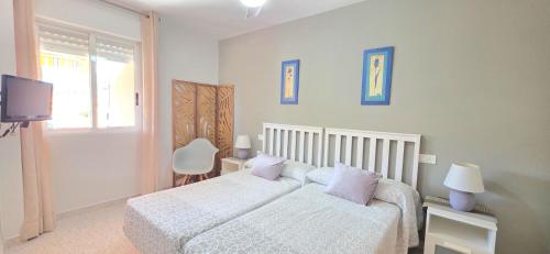 a bedroom with a white bed and a television at AYF PLAYA MORRO DE GOS in Oropesa del Mar