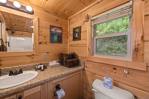 a bathroom with a sink and a toilet and a window at Cedar Heights Tiny House Log Cabin in Bryson City