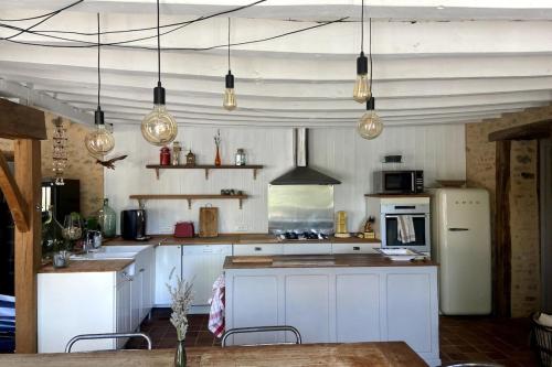 a kitchen with white cabinets and a table and lights at La Maison de Fougerolles, Renovated farmhouse in Fougerolles