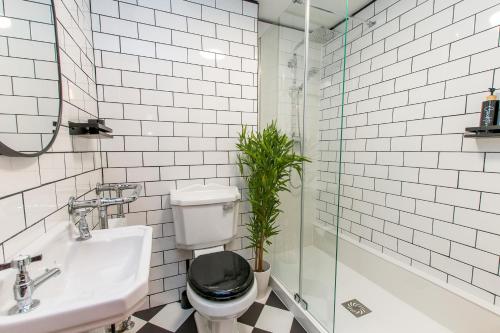 a bathroom with a toilet and a sink and a plant at Cobb's Margate Old Town Hideaway in Margate