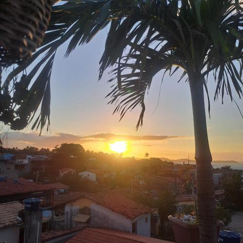 a sunset from the roof of a house with a palm tree at Casa Valhalla Pipa in Pipa