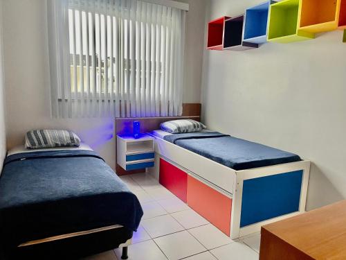 two beds in a room with colorful cabinets at Aeroporto Manaus in Manaus