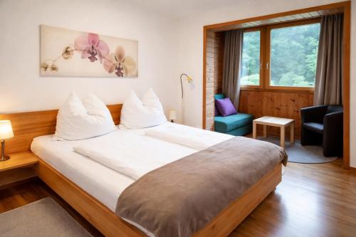 a hotel room with a large bed and a chair at Ferienwohnungen Vidoni in Bodensdorf