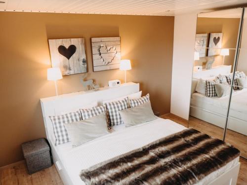 a bedroom with a large white bed and a mirror at Hillside Braunlage in Braunlage