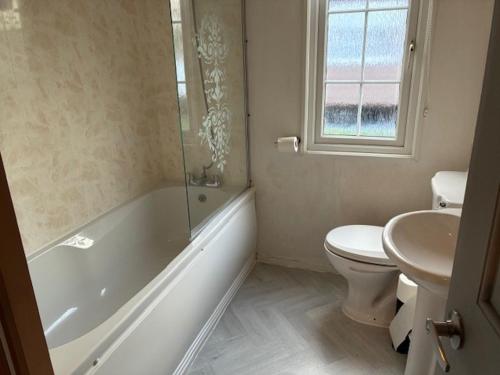 a bathroom with a tub and a toilet and a sink at Bramble Lodge in West Chevington