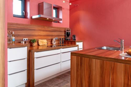 a kitchen with red walls and a wooden counter top at Gemütliches Ferienhaus in Scharbeutz