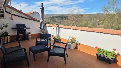 a balcony with chairs and an umbrella and a piano at Ático Vista La Sierra in Jarandilla de la Vera