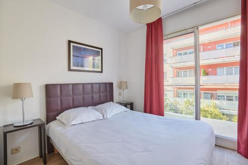 a bedroom with a bed and a large window at Appart'hôtel Odalys City - Antibes Olympe in Antibes