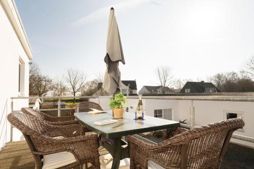 a table and chairs on a balcony with an umbrella at Dorfstraße 28 Seerose in Klausdorf