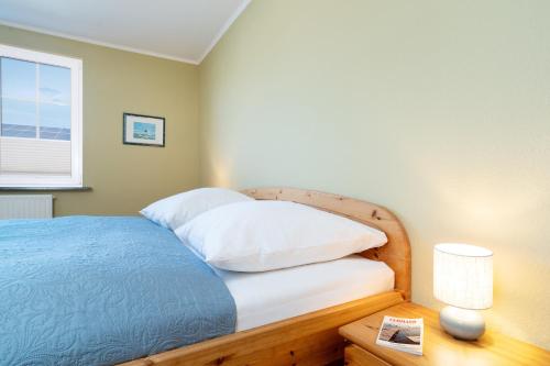 a bedroom with a bed with white pillows and a window at Dorfstraße 28 Seerose in Klausdorf