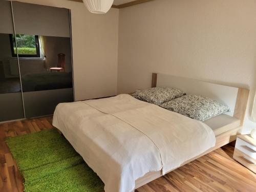 a bedroom with a white bed and a green rug at Ferienwohnung Heider in Dippoldiswalde
