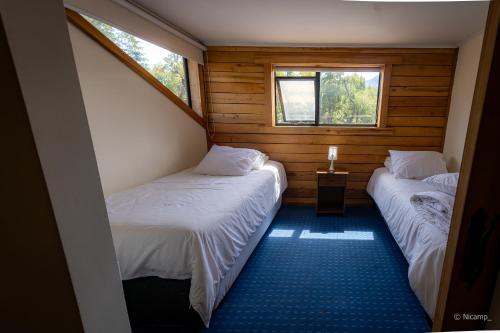 two beds in a small room with two windows at Las Bravas Lodge in Las Trancas