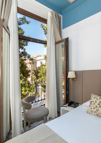a bedroom with a bed and a window with a balcony at Nest Style Granada in Granada