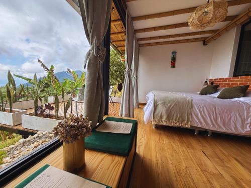 a bedroom with a bed and a large window at Casa Alta Colombia, ecolodge con vistas, Pereira in Dosquebradas