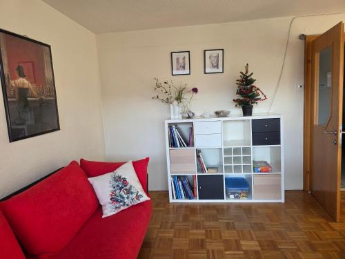 a living room with a red couch and a bookcase at Gardenia-Altach, 2-4 P, Küche, Garten, Terrasse, Parkplatz, Wifi, Ski Stellplatz in Altach