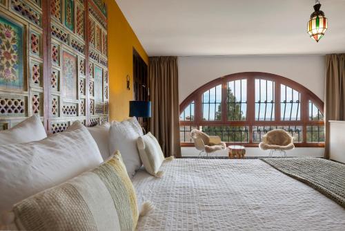 a bedroom with a large bed and a large window at Bed & Breakfast Villa Botánica in Málaga