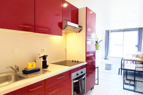 a kitchen with red cabinets and a sink at Modern in Bègles