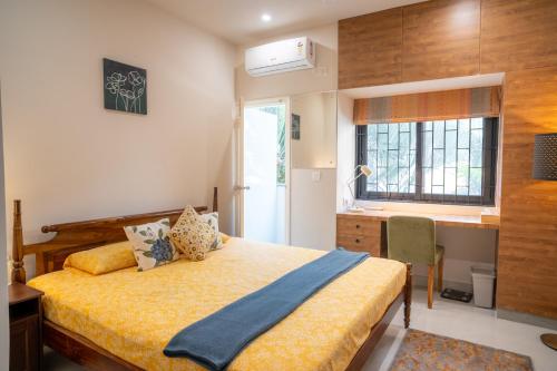 a bedroom with a bed and a desk and a window at Luho Aarambha in Bangalore