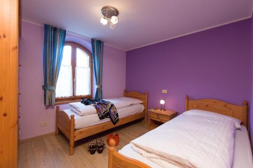 リヴィーニョにあるVilla Marilenaの紫色のベッドルーム(ベッド2台、窓付)