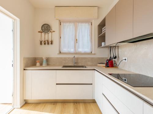 a white kitchen with a sink and a window at Apartment Lago di Luce by Interhome in Riva del Garda