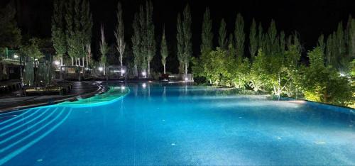 a large swimming pool with blue water at night at Avenue Park Hotel in Yusufkhona