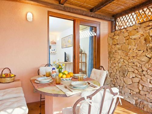 a dining room with a table and a stone wall at Apartment Mare 8 by Interhome in Porto Cervo