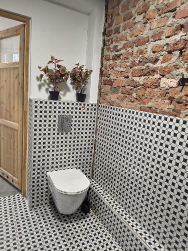 a bathroom with a toilet and a brick wall at Flores Apartament in Katowice