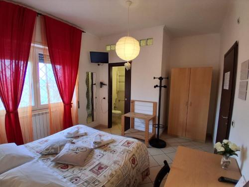 a bedroom with a bed with red curtains and a table at B&B Salviani in Acilia