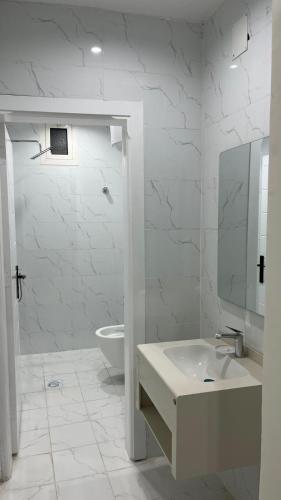 a white bathroom with a sink and a toilet at TwentyFour Seven Residence in Tabuk