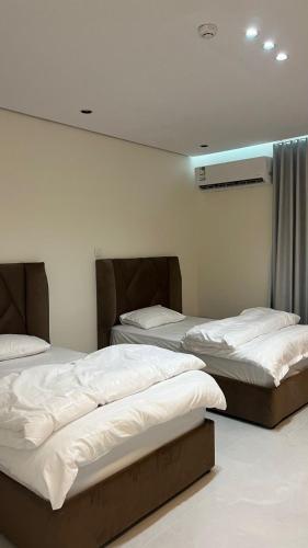 two beds in a room with white walls at TwentyFour Seven Residence in Tabuk