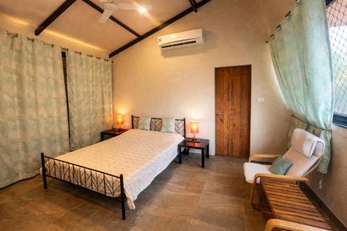 a bedroom with a bed and a chair at Enliven Homestay Alibag, Alibaug in Nagaon