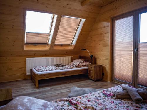 a bedroom with two beds in a wooden cabin at Ostoja Urnica in Falsztyn