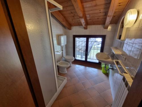 a bathroom with two toilets and a sink and a mirror at Casa Enrico in Pieve Di Ledro