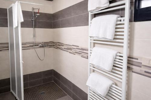 a bathroom with a shower and towels on shelves at Hotel Damma's, Dipendenza Zamagna in Cesenatico