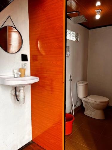 a bathroom with a toilet and a wooden door at Krincing Hills Cabin in Kalijoso