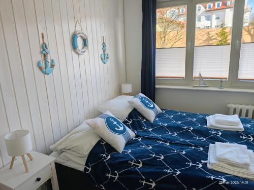 a bedroom with a bed with blue and white pillows at Gryfhaus - Pokój Kapitański, 19m2, blisko plaży, parking, wysoka ocena 9,5, 2-4 osoby in Międzyzdroje