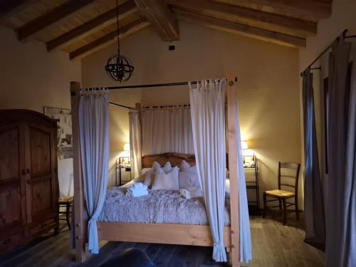 a bedroom with a canopy bed with white curtains at Agriturismo La Pina in Tarzo