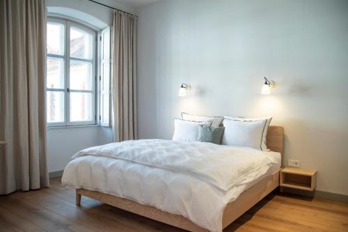 a bedroom with a bed with white sheets and a window at Hotel Josef im Kloster Beuerberg in Eurasburg