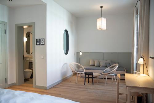 a bedroom with a couch and two chairs and a table at Hotel Josef im Kloster Beuerberg in Eurasburg