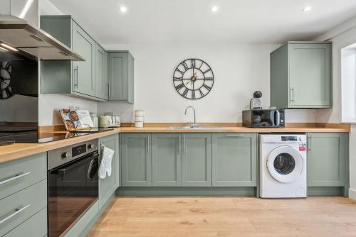 a kitchen with green cabinets and a washer and dryer at Cotswolds Vista Cirencester - Relaxed 5 Guest Home - 2 Bathroom, Parking, Garden in Cirencester