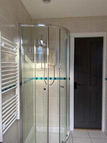 a shower with a glass door in a bathroom at Craigdarroch Guest House in Contin