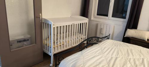 a white crib in a room with a bed at Replonges entre A6 et A40 in Replonges